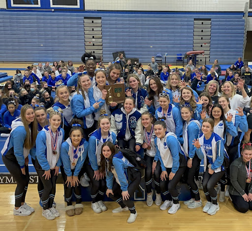 Photo courtesy of @BerlinBearsGym on Twitter: The gymnastics team crowds around the podium as they claim their trophy for first place at districts. At this meet, the team broke their team record with a 146.025. 