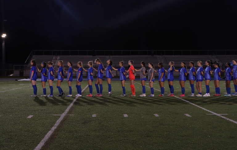 The girls soccer team all stand together listening to the national anthem play. The girls were all excited to play in their senior night game against Olentangy.