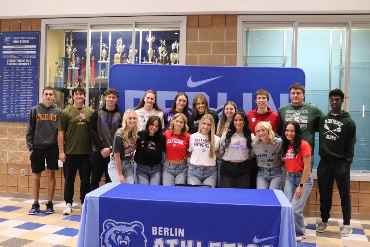 Berlin athletes pose for a photo before they sign their NIL agreements. Each athlete had a table decorated in the gym. These 17 students have signed with 16 different colleges.